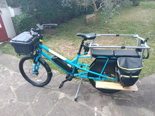 Vélo cargo bleu sur une allée pavée.