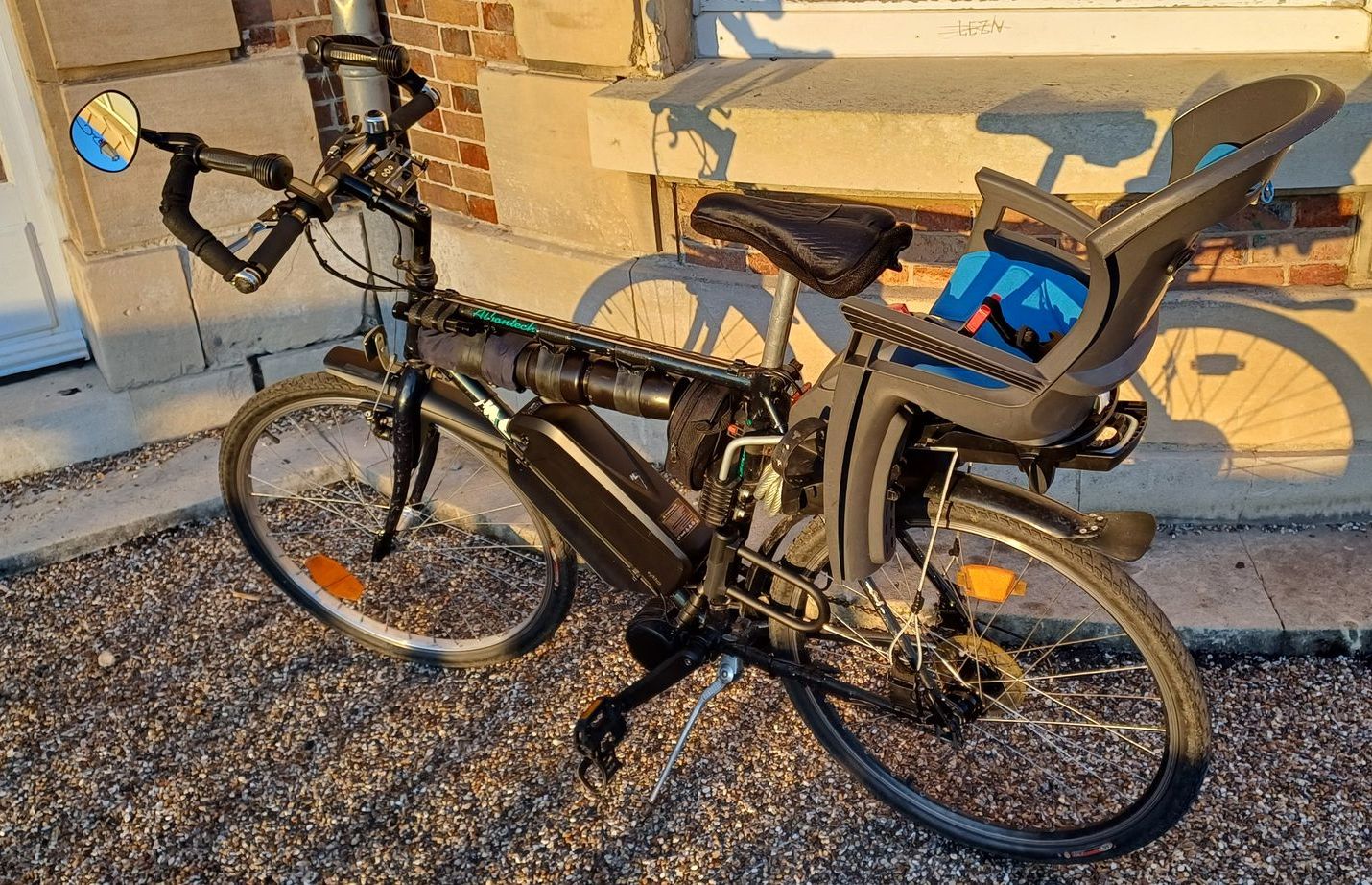 Vélo avec siège enfant sur parking pavé.