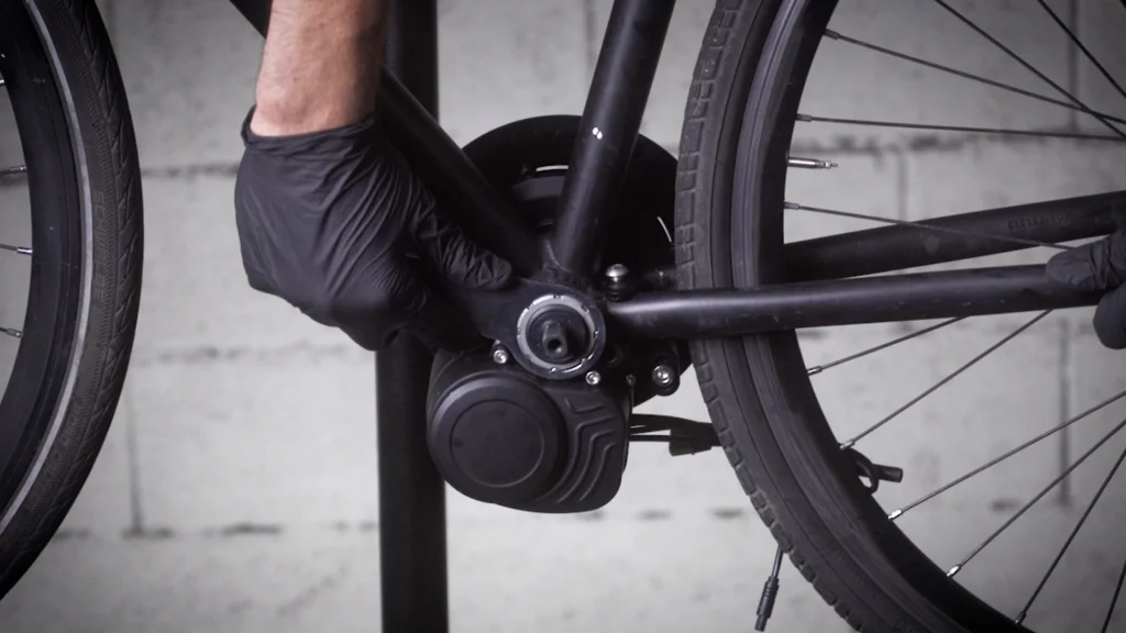 Réparation du pédalier d'un vélo par une main gantée.