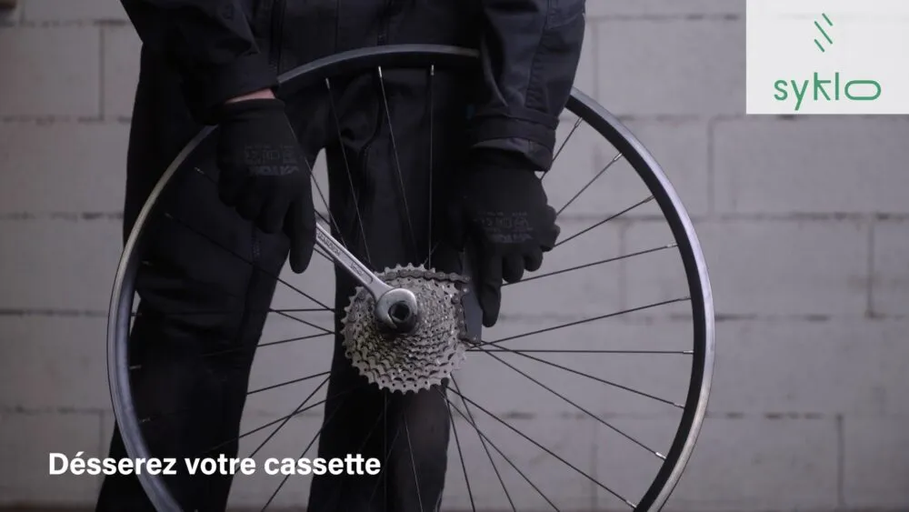 Homme desserrant cassette de vélo avec clé.