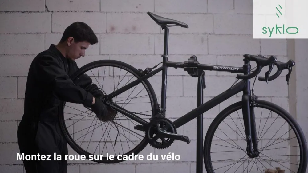 Homme assemble roue sur vélo.