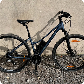 Vélo hybride noir appuyé contre un mur.