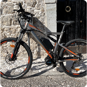 Vélo électrique devant mur de pierre